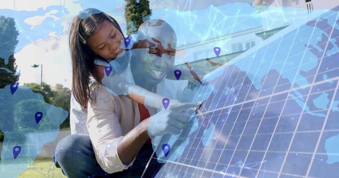 Adult pointing solar cell while child on back, map overlay initiating pins linking energy grid
