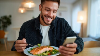 A cheerful young Hispanic man enjoys a healthy meal while using his smartphone.