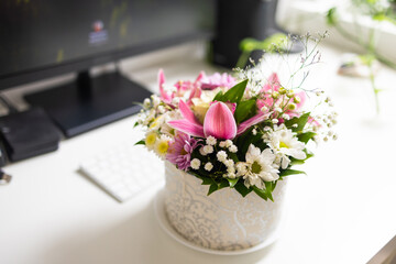 Floral bouquet near computer monitor and keyboard. Harmony of work, nature, and aesthetic minimalism in home office.