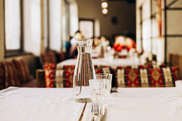 Elegant water carafe and glasses on restaurant table in soft daylight.