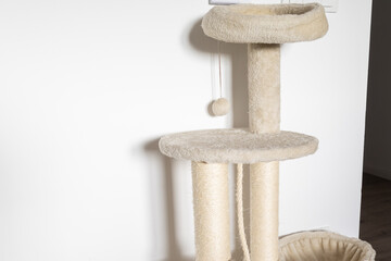 Beige cat tree near wall. Comfort, playfulness, and everyday atmosphere of pet-friendly living space.