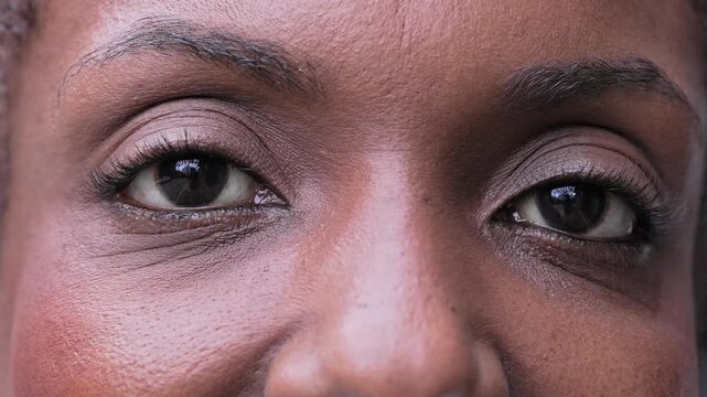 Close-Up Of Black Woman’s Eyes Looking At Camera With Gentle Smile And Warm Expression Showing Subtle Emotion In Soft Light