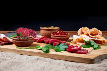 Gourmet platter with cold cuts, cherries, olives, and sauce on a dark background. Ideal for culinary branding, editorial photography, or premium food content.