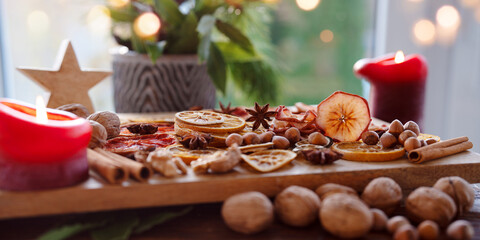 Dried citrus fruits and apple rings with nuts on rustic wood. Background for christmas preparations and decorations.