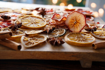 Dried citrus fruits and apple rings with spices on rustic wood. Preparations for christmas baking and hot drinks.