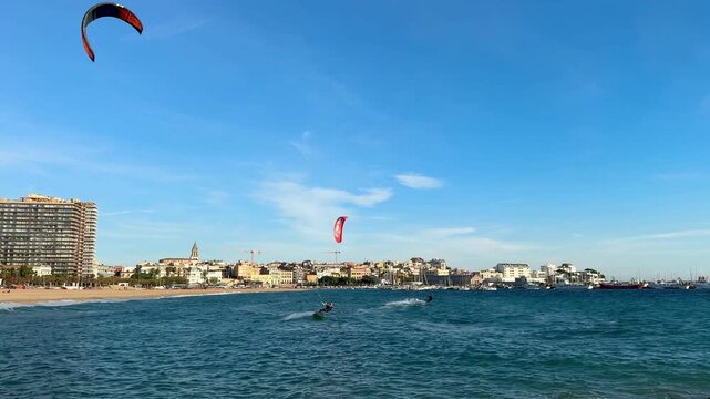 Adventurous kite surfers gliding over turquoise waves on the Costa Brava. Summer energy, action and ocean vibes ideal for tourism and outdoor advertising.