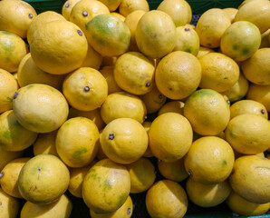 A vibrant close-up of numerous fresh, ripe yellow lemons piled high, ready for sale.