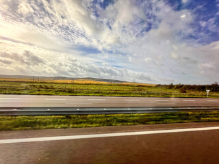 Driving on highway through green countryside under cloudy sky