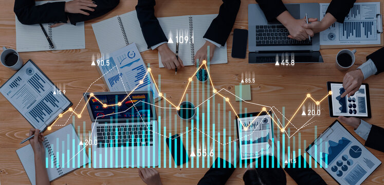 A diverse group of business professionals engages in a collaborative meeting, analyzing financial data displayed on devices and documents, highlighting teamwork. Scalp - Powered by Adobe