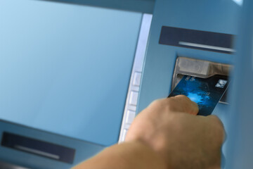 Man with bank card using modern cash machine, closeup. ATM