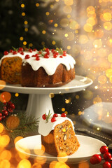 Tasty Christmas cake with red currants and fir branches on table. Bokeh lights