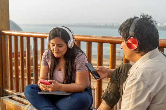 Young couple enjoying technology and music outdoors