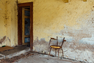 une vieille chaise cass&eacute;e et abandonn&eacute;e dans un squat. Chaise de guetter dans la banlieue. D&eacute;chet dans la ville. Mur d&eacute;cr&eacute;pi dans une ancienne maison d&eacute;sert&eacute;e
