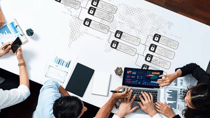 A diverse business team engages in a data analysis session with charts and graphs on the laptop, showcasing teamwork and strategic planning in a modern workspace. Raster
