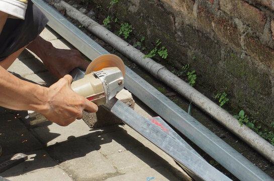 A man is cutting iron using a grinding machine while squatting, but his work process is still careful and skilled in carpentry
