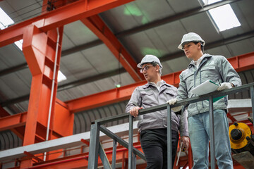 Fototapeta premium Engineers inspecting equipment and discussing maintenance procedures inside a modern industrial factory. Safety, teamwork, and production quality control in a manufacturing plant.