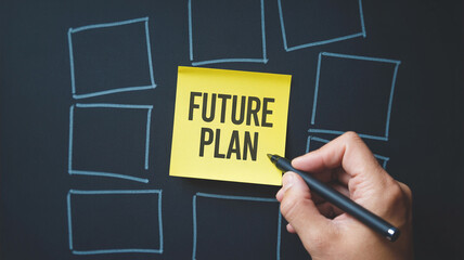 Hand holding pen near future plan sticky note with drawn boxes on a dark surface background