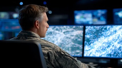 Army commander seated before dual surveillance displays showing heat maps and strategic terrain, darkened war room environment symbolizing security analysis
