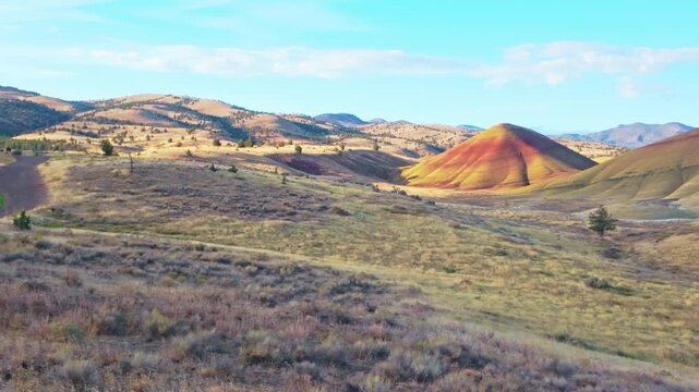 Vivid panoramic view of Painted Hills' vibrant red, gold, black layers from an elevated viewpoint at John Day Fossil Beds National Monument at sunrise