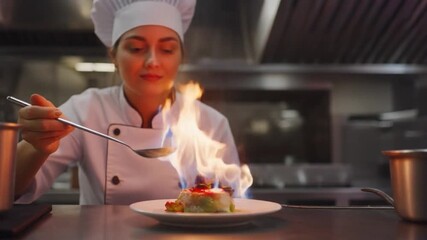 Female culinary professional carefully garnishing plated dessert with sauce in commercial kitchen