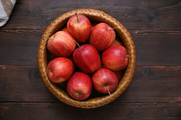 basket with ripe red apples on a wooden table, flat lay