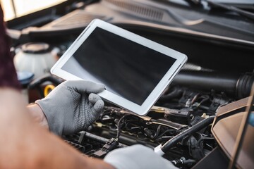 Naklejka premium Mechanic uses a digital table to record error engine checks