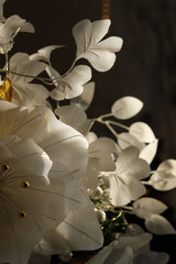 Elegant white Christmas flowers decorated with golden elements on a dark background. The flowers are softly illuminated, creating a festive and luxurious holiday mood