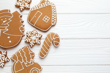 Tasty gingerbread cookies on white wooden table, flat lay. Space for text