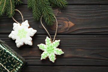 Fototapeta premium Tasty gingerbread cookies, gift box and fir tree branches on wooden table, flat lay. Space for text