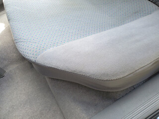 Close-up of rear seat in 1990s sedan, featuring soft grey upholstery with subtle blue dotted fabric pattern. The interior design typical of vintage cars, illustrating automotive retro interiors 90s