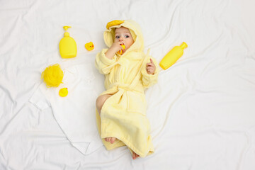 Cute baby in bathrobe and bathroom accessories on bed, top view