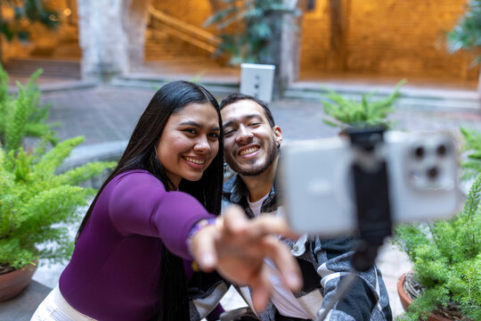 Latino couple taking a selfie using smartphone while traveling on vacation trip