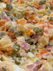 Close-up of traditional Russian Olivier salad with diced vegetables and creamy dressing background