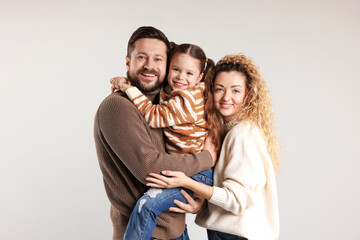 Portrait of happy family hugging on grey background