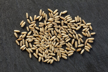 Obraz premium Whole oat grains scattered on a dark background. Natural texture, organic cereal, ideal for food, agriculture, and nutrition visuals