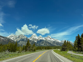 Scenic landscape view of a snow capped mountains from a car driving on a road through the Grand Teton national Park. No people.