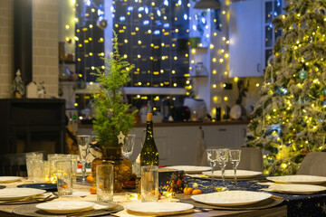 Festive interior of house is decorated for Christmas and New Year in loft style with black stove, fireplace, Christmas tree. Warm studio room with set table, burning wood, cozy and heating of home