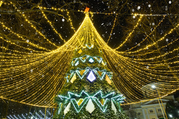High city Christmas tree with a mushroom cap made of garlands, glows at night on the street. Christmas, New Year, decoration of the city. 