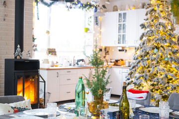 Festive interior of house is decorated for Christmas and New Year in loft style with black stove, fireplace, Christmas tree. Warm studio room with set table, burning wood, cozy and heating of home