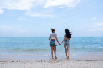 Two cheerful young women friends enjoying a fun day at the beach, smiling and posing happily by the sea. Perfect for friendship, summer vacation, travel, lifestyle, and happiness concepts.