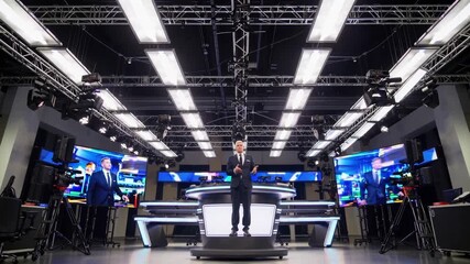 news anchor stands in studio under linear LED lights, surrounded by video walls and camera rigs, presenter at central desk delivering live report, production crew and control monitors visible, sleek - Powered by Adobe