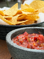 Crispy tortilla chips served with fresh salsa in a stone bowl at a vibrant outdoor setting