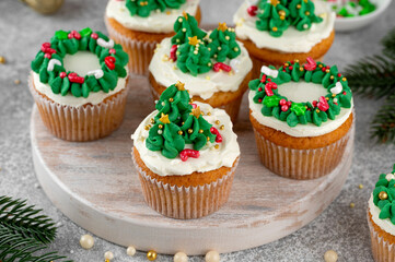 Christmas tree and wreath shaped cupcakes with candy sprinkles on top. Christmas dessert on a light concrete background.