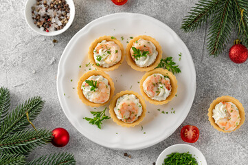 Christmas food. Tartlets with shrimp, cream cheese, garlic and parsley on a wooden board on gray concrete background.