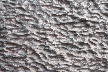 Close-up of a dark, industrial, hammered metal surface with a rough, craggy, abstract texture. Metallic gray background for engineering or strength concepts.
