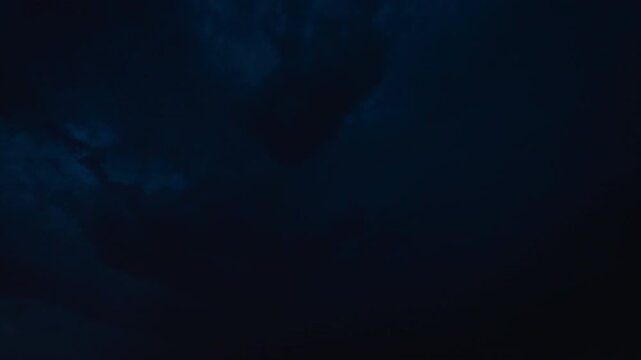 Distant horizon glowing as lightning dances across dark clouds in the night sky 