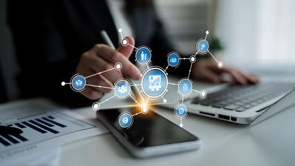An individual interacts with a smartphone and laptop, showcasing a digital network and data analysis concept in a modern business environment, emphasizing connectivity and technology. Tessel