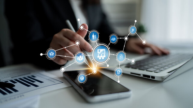 An individual interacts with a smartphone and laptop, showcasing a digital network and data analysis concept in a modern business environment, emphasizing connectivity and technology. Tessel