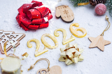 Festive New Year composition with golden 2026 numbers surrounded by Christmas ornaments, bows, and snow. Concept for holiday joy, celebration and the beginning of a new year.