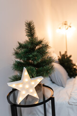 bedroom christmas decor. home interior for new years celebration. festive wreath, christmas tree. white sheets. pretty